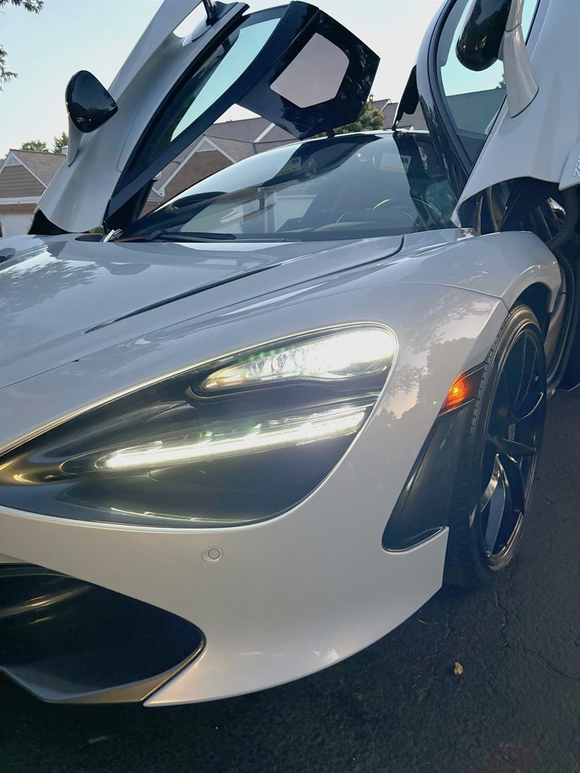 A white McLaren 720S with doors raised, freshly detailed.