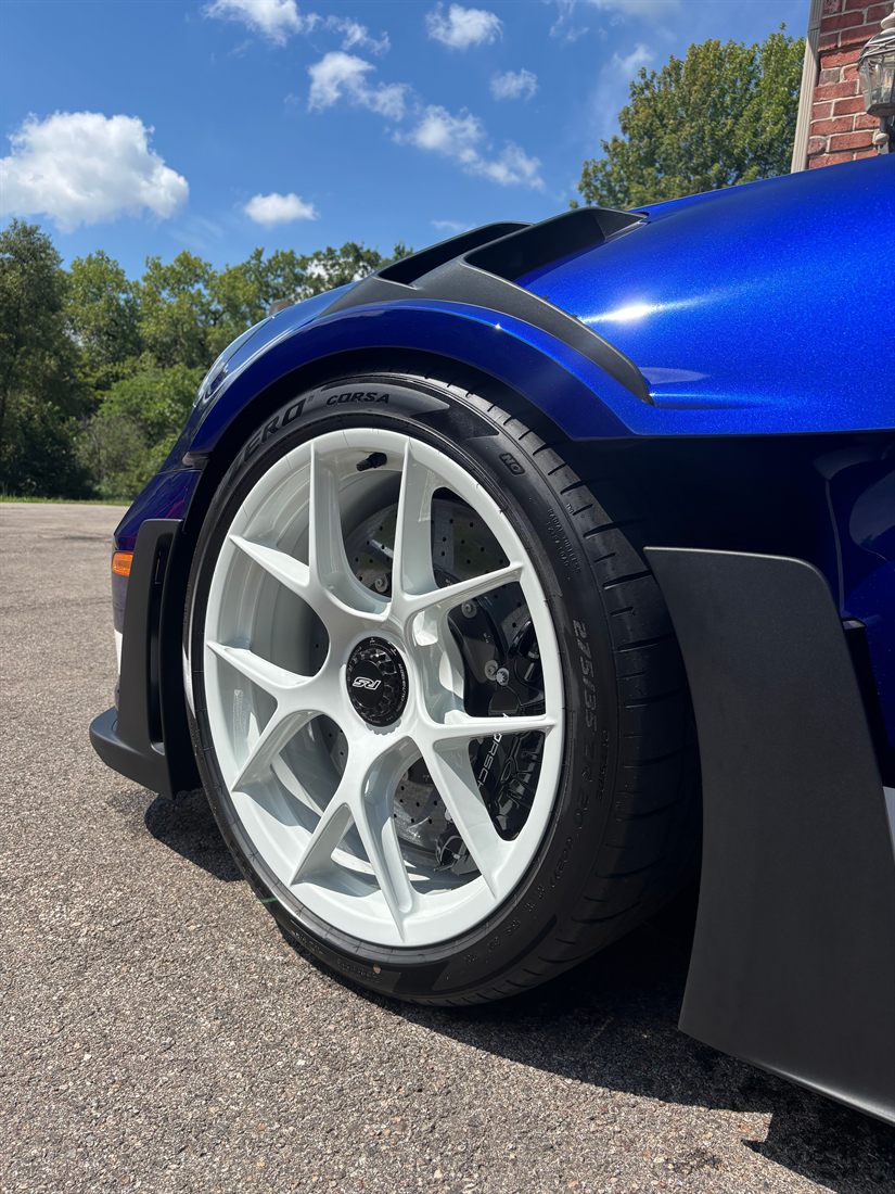 A close-up of a forged wheel and brake on a blue sports car.